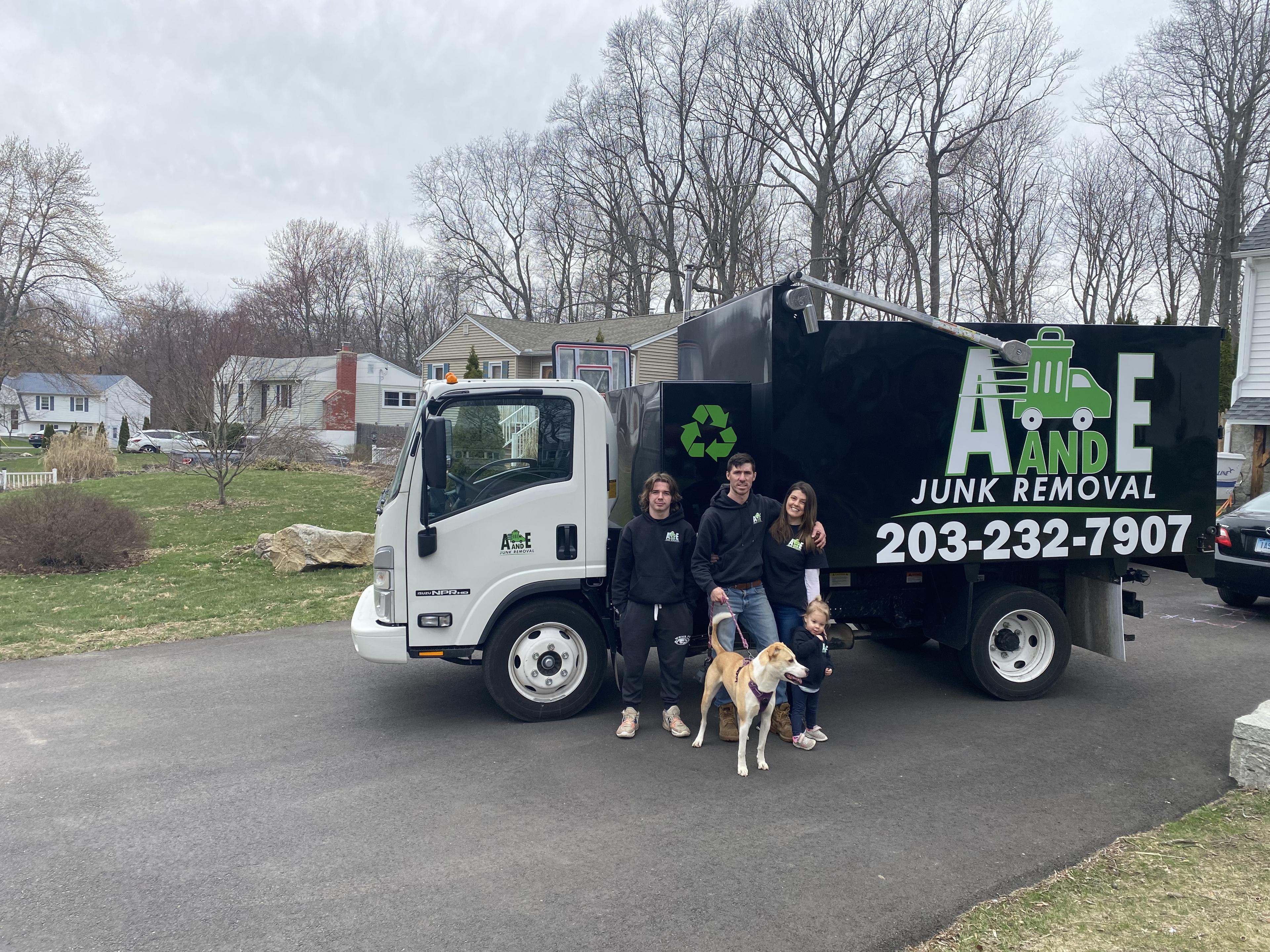 owner of a and e junk removal standing by truck with family