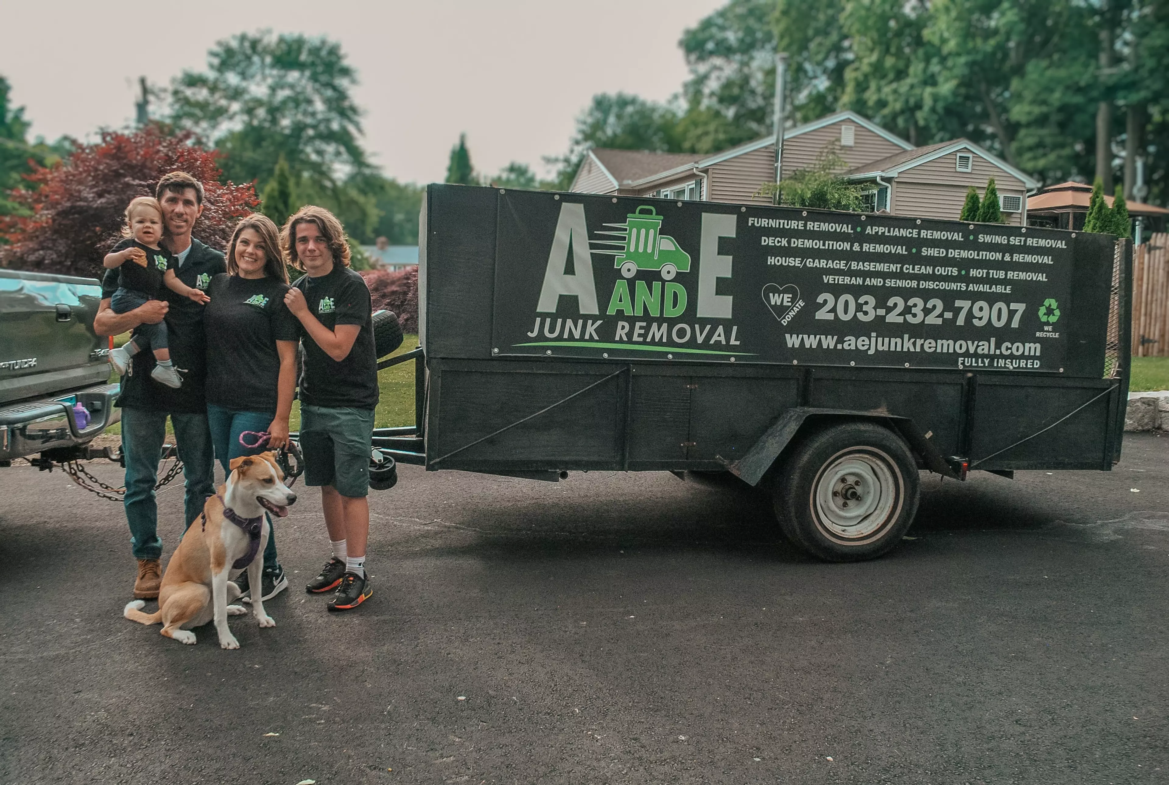 owner of a and e junk removal standing by truck with family