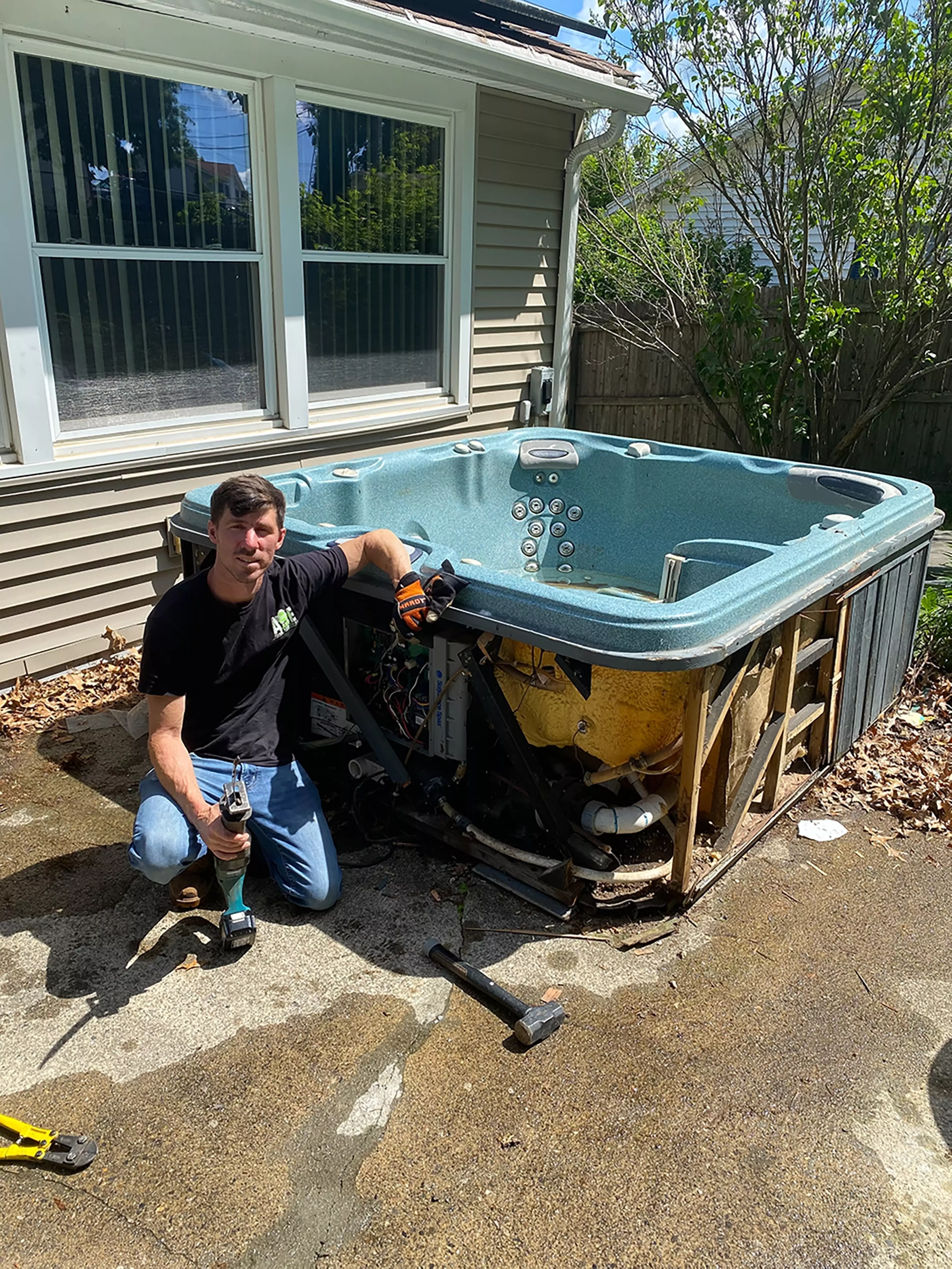 owner Gary Henry kneeling by a hot tub about to be removed